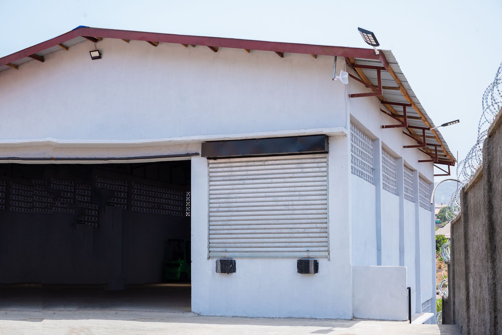 Loading bay with roller shutter and open drive-in bay